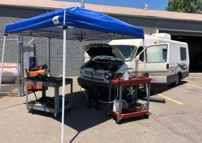 Working on an RV engine under an outdoor canopy